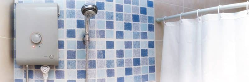 A wall-mounted water heater installed beside a shower in a tiled bathroom, a common setup in Singapore HDB flats and condos.